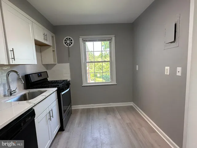 a kitchen that has a sink a stove and wooden floor