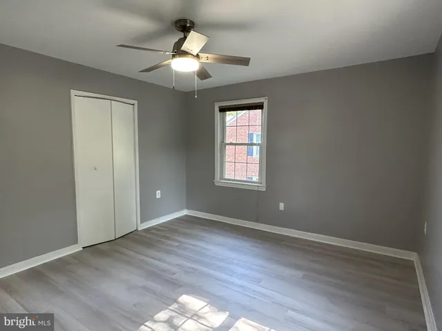 an empty room with wooden floor chandelier fan and windows
