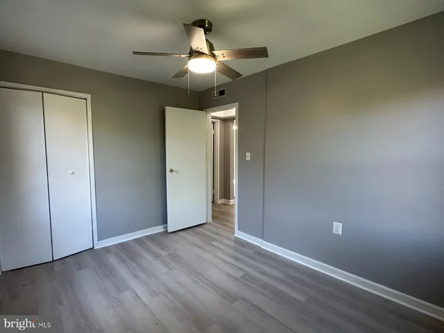 an empty room with wooden floor fan and windows
