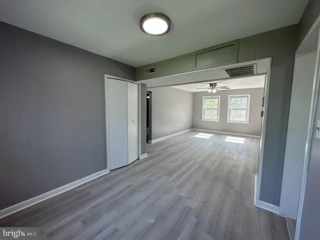 an empty room with wooden floor and windows