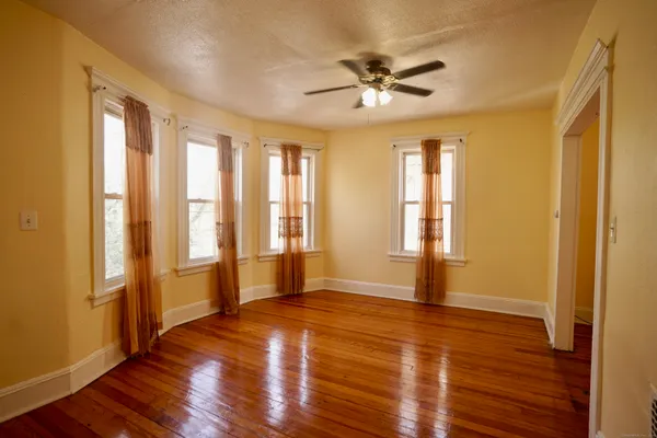 a view of an empty room with wooden floor and a window