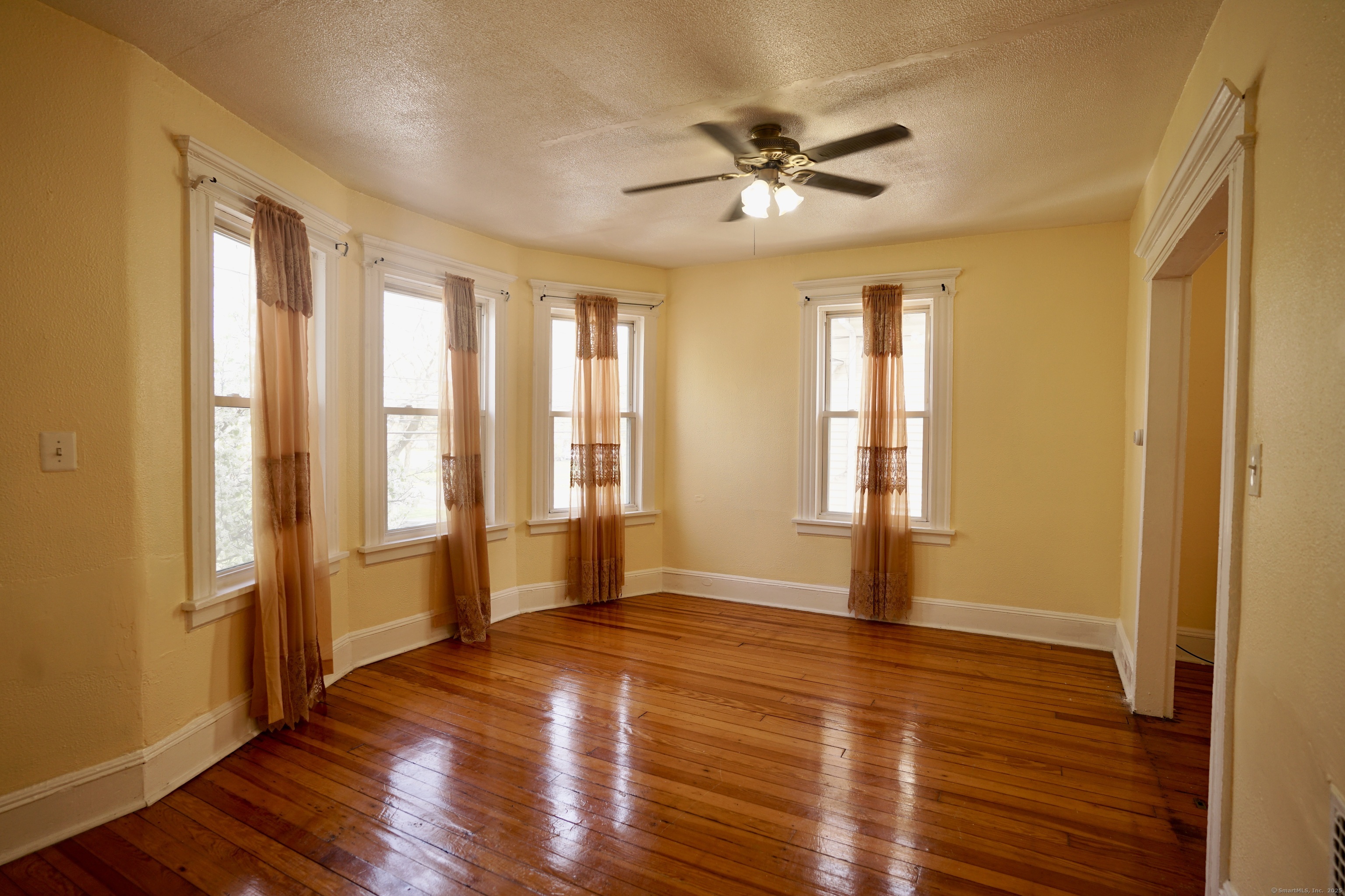 a view of an empty room with wooden floor and a window