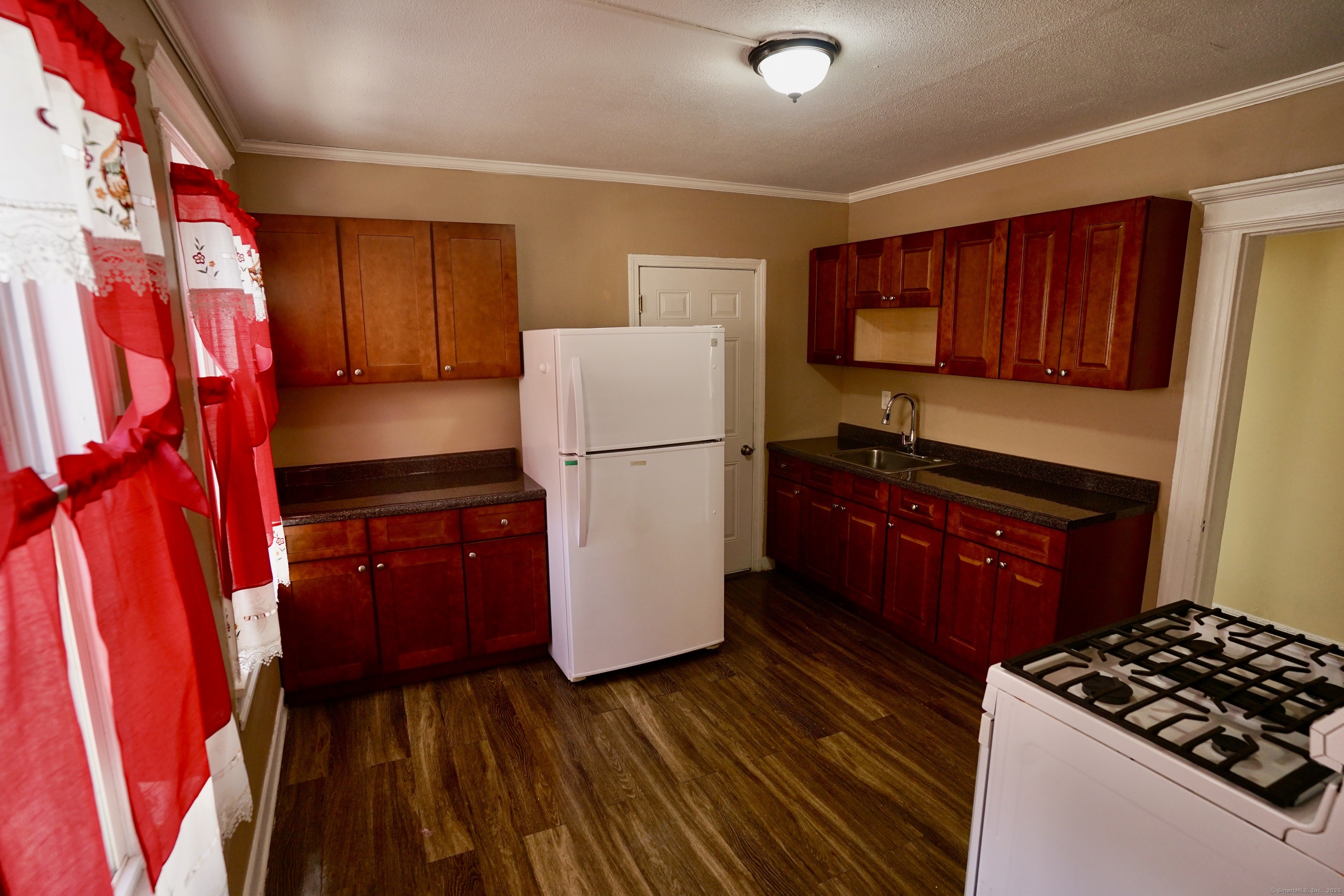 744 Boston Avenue Bridgeport, CT 06610 - Photo 5 of 10 a kitchen with a refrigerator stove and wooden cabinets