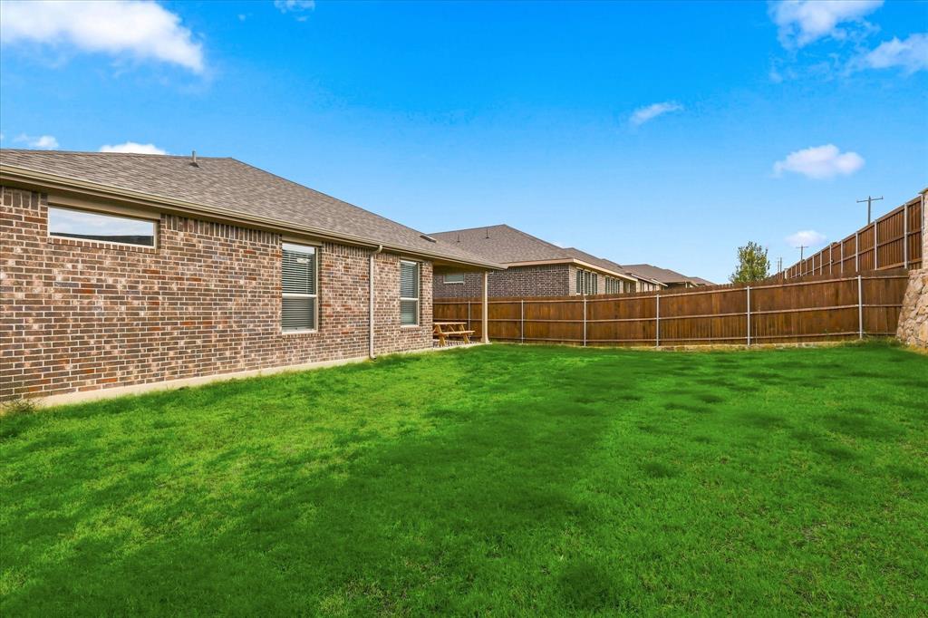 141 Medina Lane Rhome, TX 76078 - Photo 31 of 36 Expansive green lawn with a brown brick exterior, brown shingle roofing, and a privacy fence