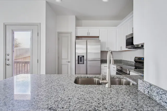 a kitchen with stainless steel appliances granite countertop a refrigerator a stove and a sink