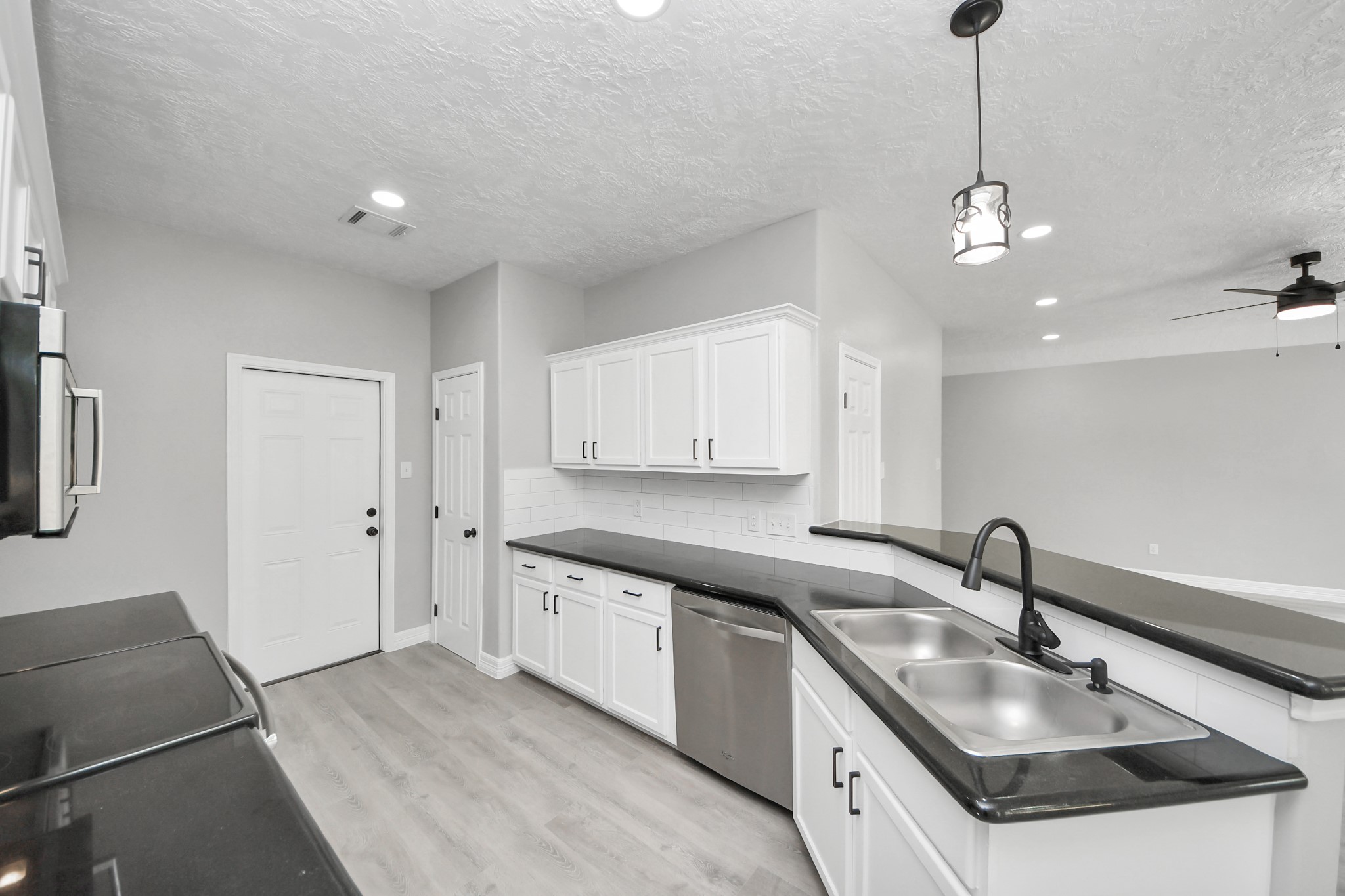 1105 East Kyle Road Clute, TX 77531 - Photo 10 of 44 This home features a modern kitchen with sleek black countertops, white cabinetry, and stainless steel appliances.