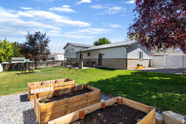 415 360 East Salem, UT 84653 - Photo 16 of 20 Spacious backyard featuring two raised garden beds, a gravel path, and a manicured lawn