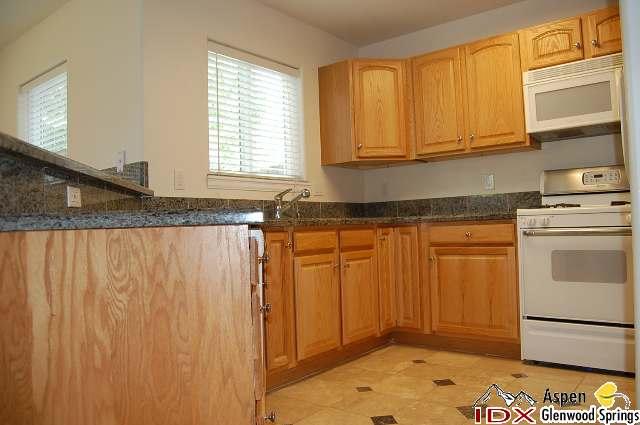 1056 Village Road Carbondale, CO 81623 - Photo 3 of 9 a kitchen with granite countertop white cabinets and white appliances