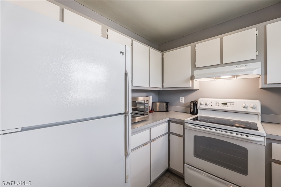 2885 Triggerfish Street Cape Coral, FL 33993 - Photo 26 of 35 a kitchen with stainless steel appliances white cabinets and white appliances