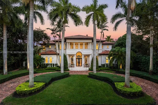a front view of a house with a garden and trees