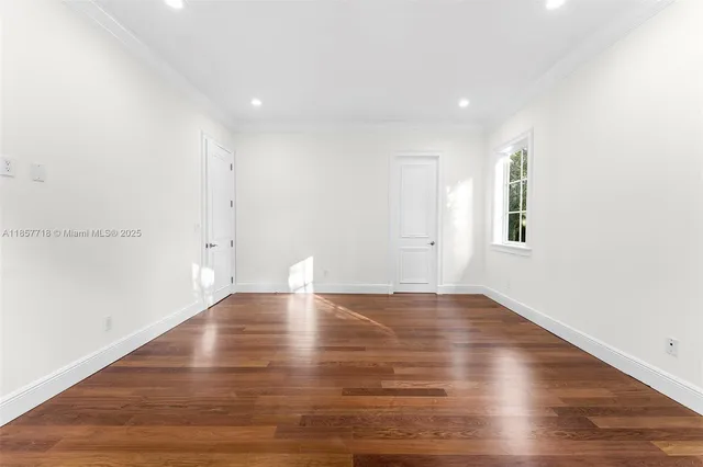 a view of an empty room with wooden floor and windows