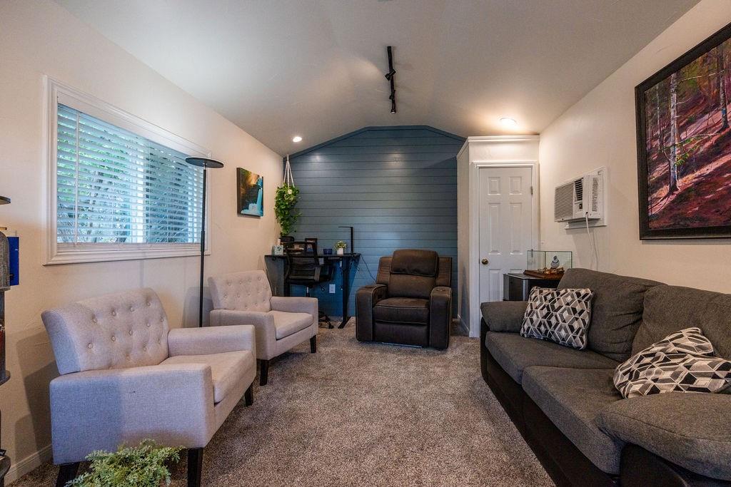 384 Ft Graham Road Waco, TX 76705 - Photo 27 of 36 Carpeted living space with a window featuring blinds, track lighting, and a paneled accent wall