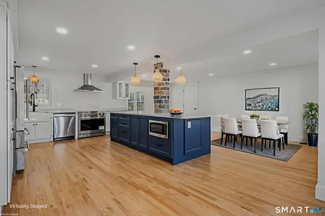 a living room with stainless steel appliances kitchen island granite countertop wooden floors and a view of living room