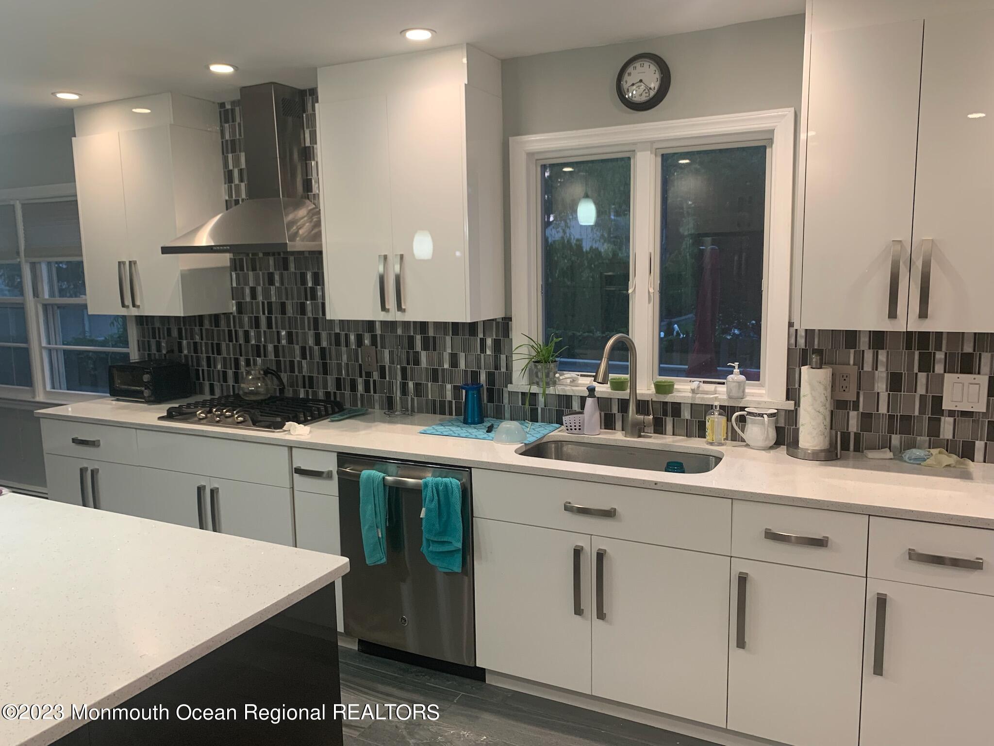 293 Lawrence Avenue Oakhurst, NJ 07755 - Photo 3 of 18 a kitchen with a sink dishwasher a stove and white cabinets with wooden floor