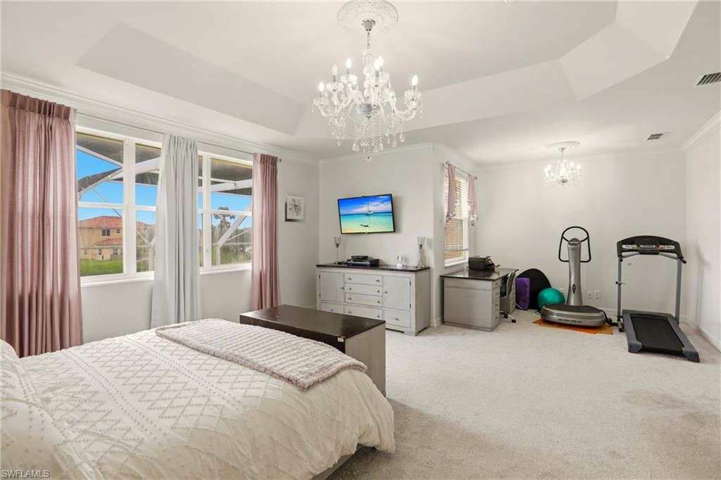 2150 Khasia Point Naples, FL 34119 - Photo 11 of 39 Carpeted bedroom with a chandelier, a tray ceiling, and ornamental molding