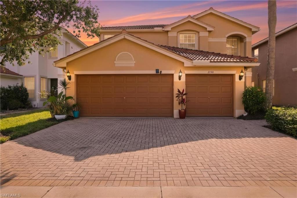 2150 Khasia Point Naples, FL 34119 - Photo 3 of 39 Mediterranean / spanish-style home with decorative driveway, stucco siding, a tile roof, and an attached garage
