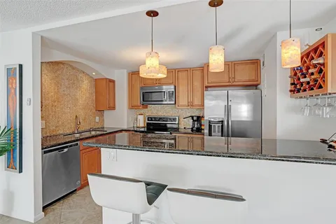 a kitchen with stainless steel appliances granite countertop a sink a refrigerator and a wooden floor