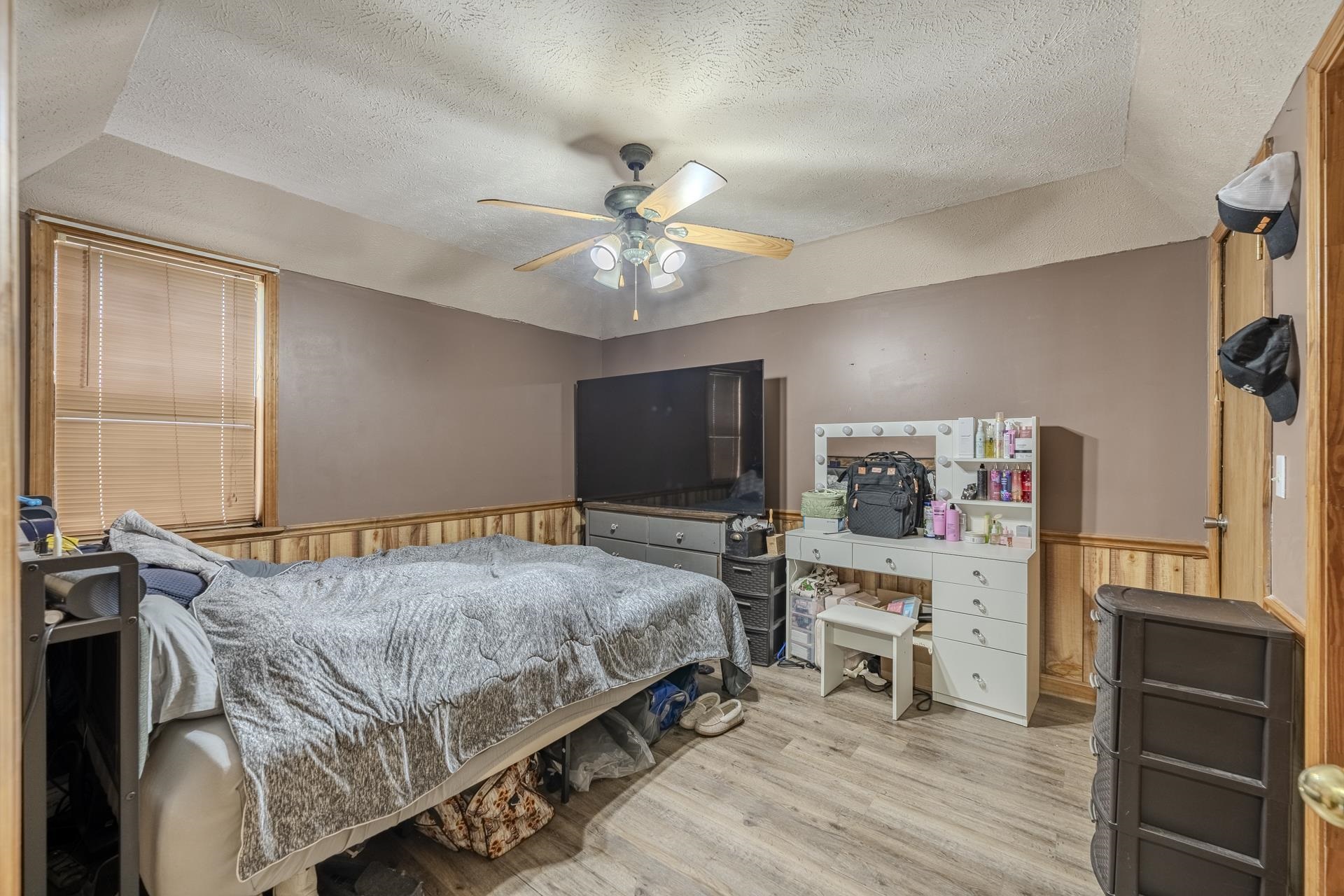 635 Pompeys Branch Road Savannah, TN 38372 - Photo 15 of 26 Bedroom featuring a wainscoted wall, wooden walls, a textured ceiling, a ceiling fan, and light wood finished floors
