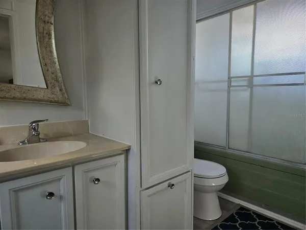 a bathroom with a granite countertop toilet sink and mirror