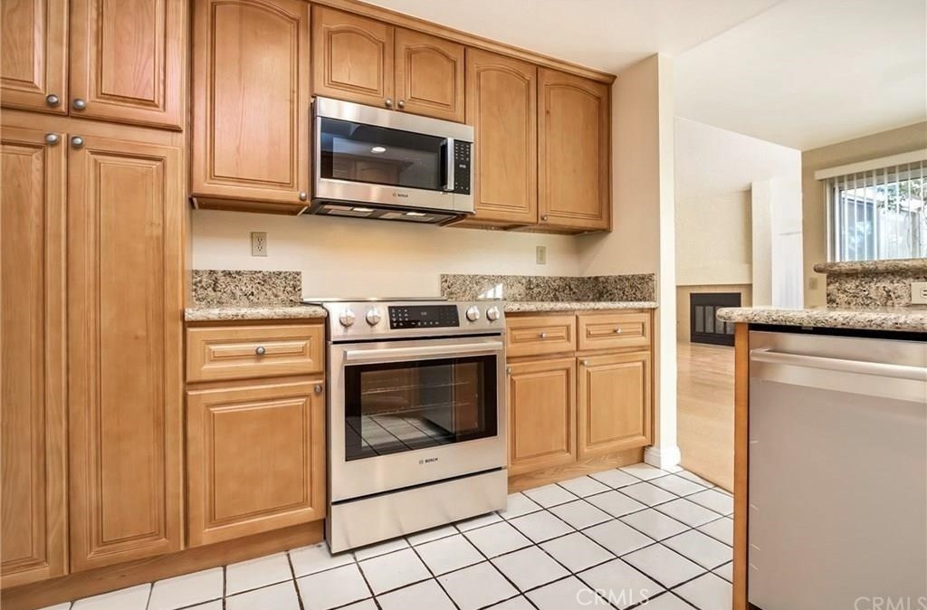 341 Stanford Court, Unit 26 Irvine, CA 92612 - Photo 5 of 24 a kitchen with stainless steel appliances granite countertop a stove microwave and cabinets