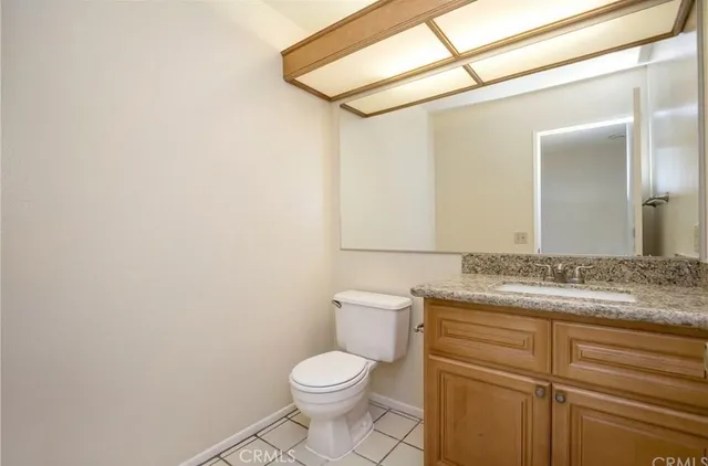 a bathroom with a granite countertop toilet sink and mirror