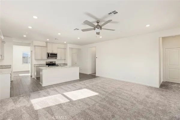 a view of kitchen with stainless steel appliances kitchen island sink refrigerator and white cabinets