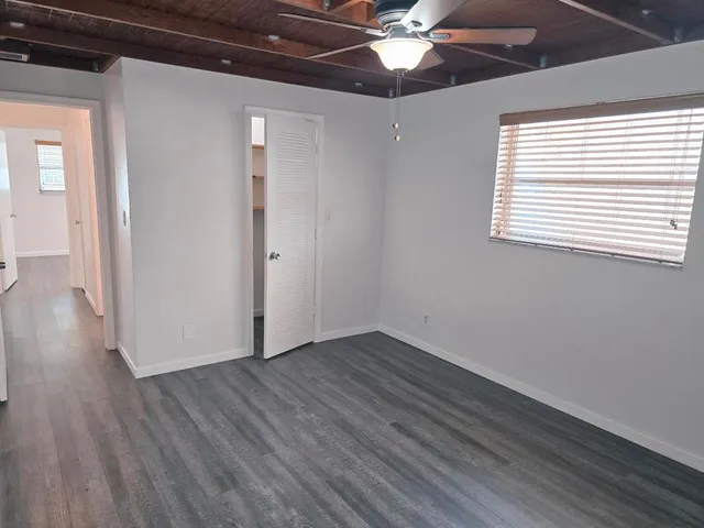 a view of an empty room with wooden floor and a window