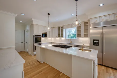 a kitchen with stainless steel appliances a sink a stove a refrigerator and island