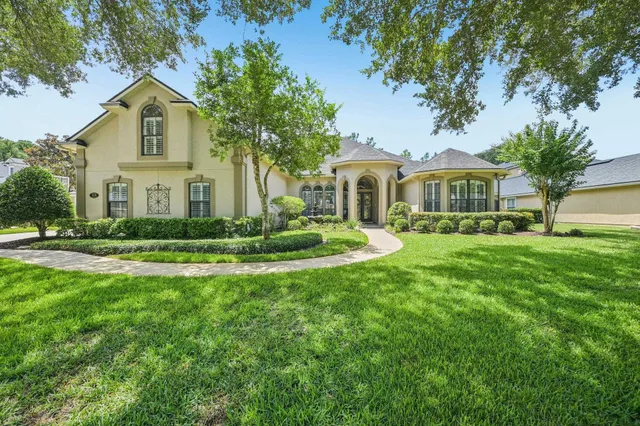 a front view of a house with a garden and trees