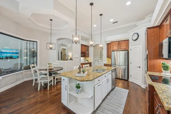 a kitchen with stainless steel appliances granite countertop a stove a sink a refrigerator and island wooden floor