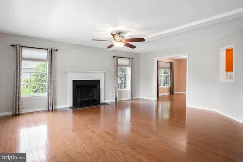 a view of an empty room with wooden floor fireplace and a window