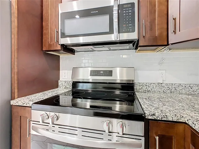 a kitchen with granite countertop white cabinets and stainless steel appliances