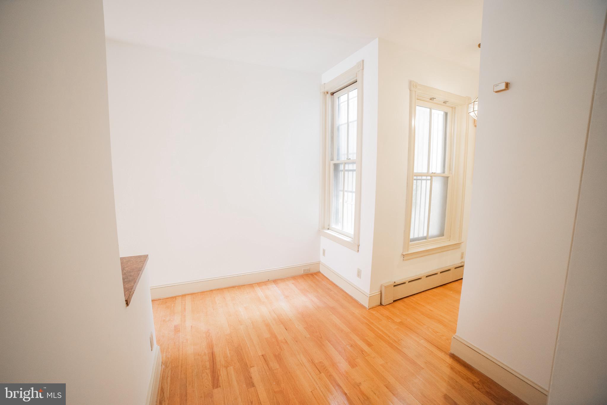2408 Spruce Street, Unit 1F Philadelphia, PA 19103 - Photo 8 of 11 a view of an empty room with wooden floor and a window