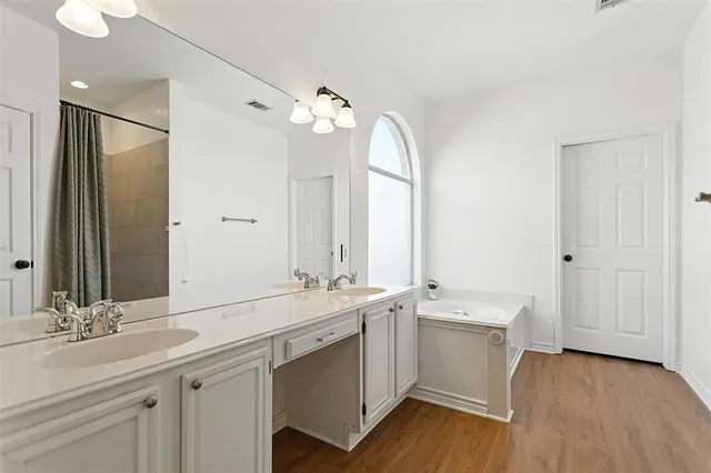 a bathroom with a double vanity sink a mirror and a bathtub