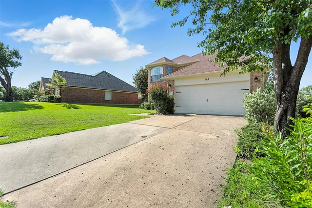 a view of a white house next to a yard and a large tree