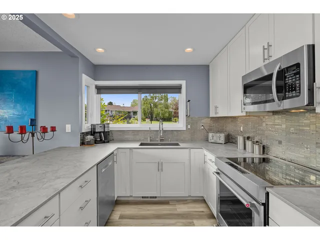 a kitchen with stainless steel appliances a sink a stove a microwave a sink and cabinets