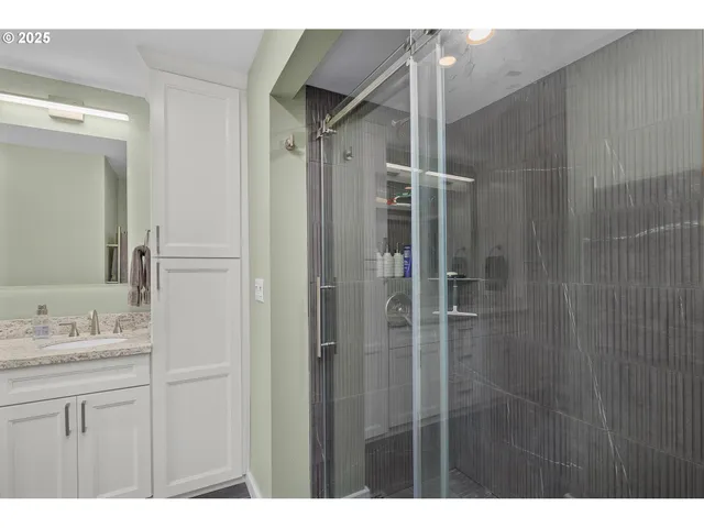 a bathroom with a shower sink vanity and mirror