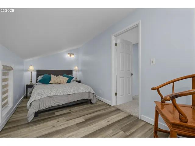 a bedroom with a bed a mirror with wooden floor