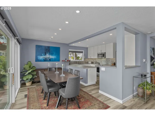 a living room with furniture a potted plant and kitchen view