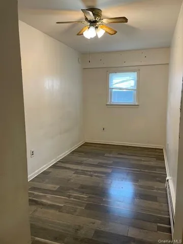 en empty room with wooden floor fan and window