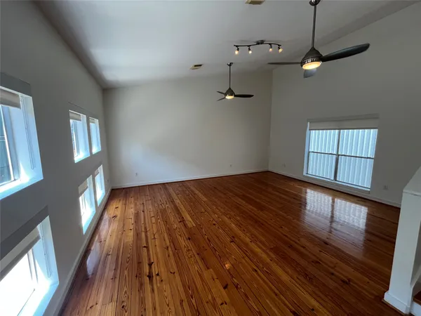 a view of empty room with wooden floor and fan