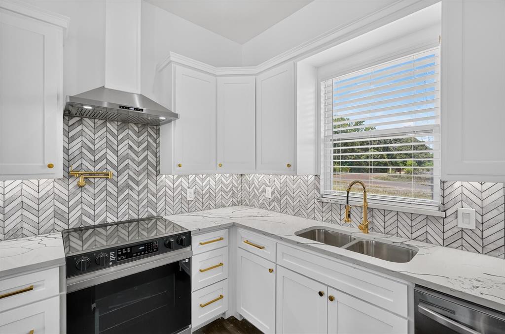 102 Shadywood Road Trinidad, TX 75163 - Photo 9 of 24 Kitchen featuring white cabinetry with gold hardware, a herringbone pattern tile backsplash, light-toned countertops, and a stainless steel appliance suite including a range and hood