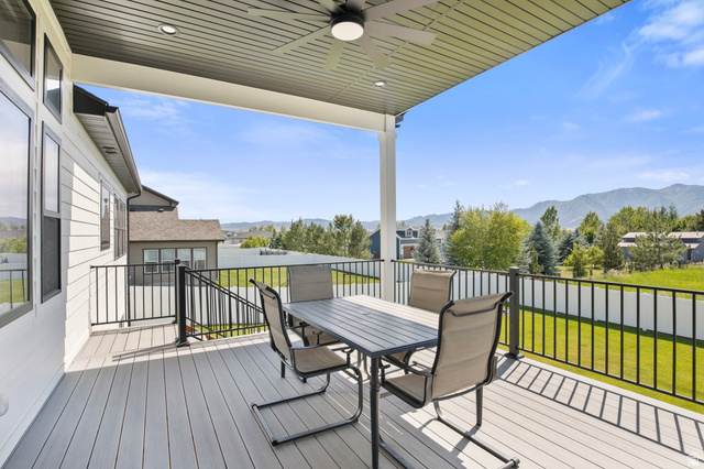 3111 South 1250 West Logan, UT 84321 - Photo 40 of 51 Spacious covered deck featuring composite decking, black metal railings, a ceiling fan, and recessed lighting, all overlooking a mountain range