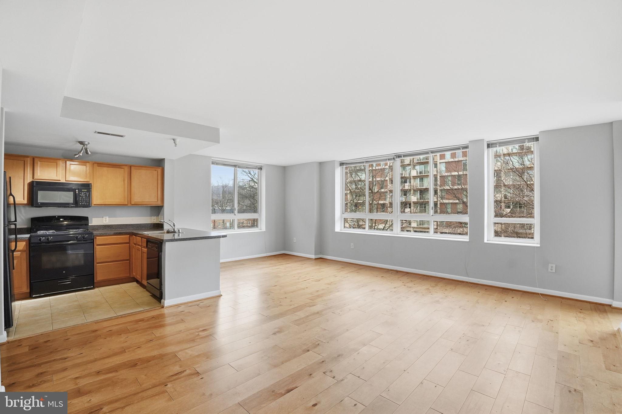 a view of a kitchen with granite countertop a stove top oven a sink with wooden floor and cabinets