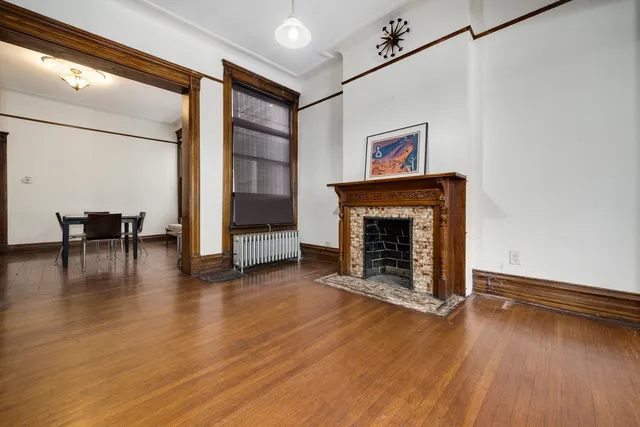 an empty room with wooden floor fireplace and windows