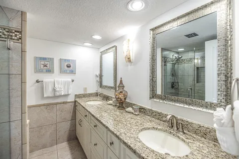 a bathroom with a granite countertop double vanity sink and mirror