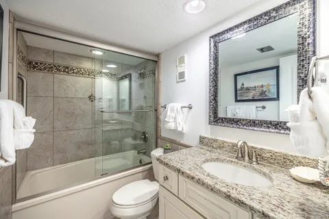 a bathroom with a granite countertop sink toilet and shower