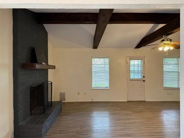 a view of an empty room with wooden floor and a fireplace