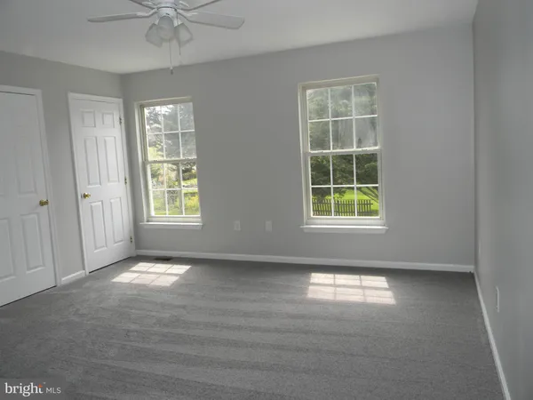 en empty room with windows and chandelier fan