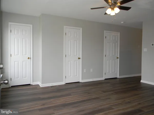 an empty room with wooden floor and ceiling fan